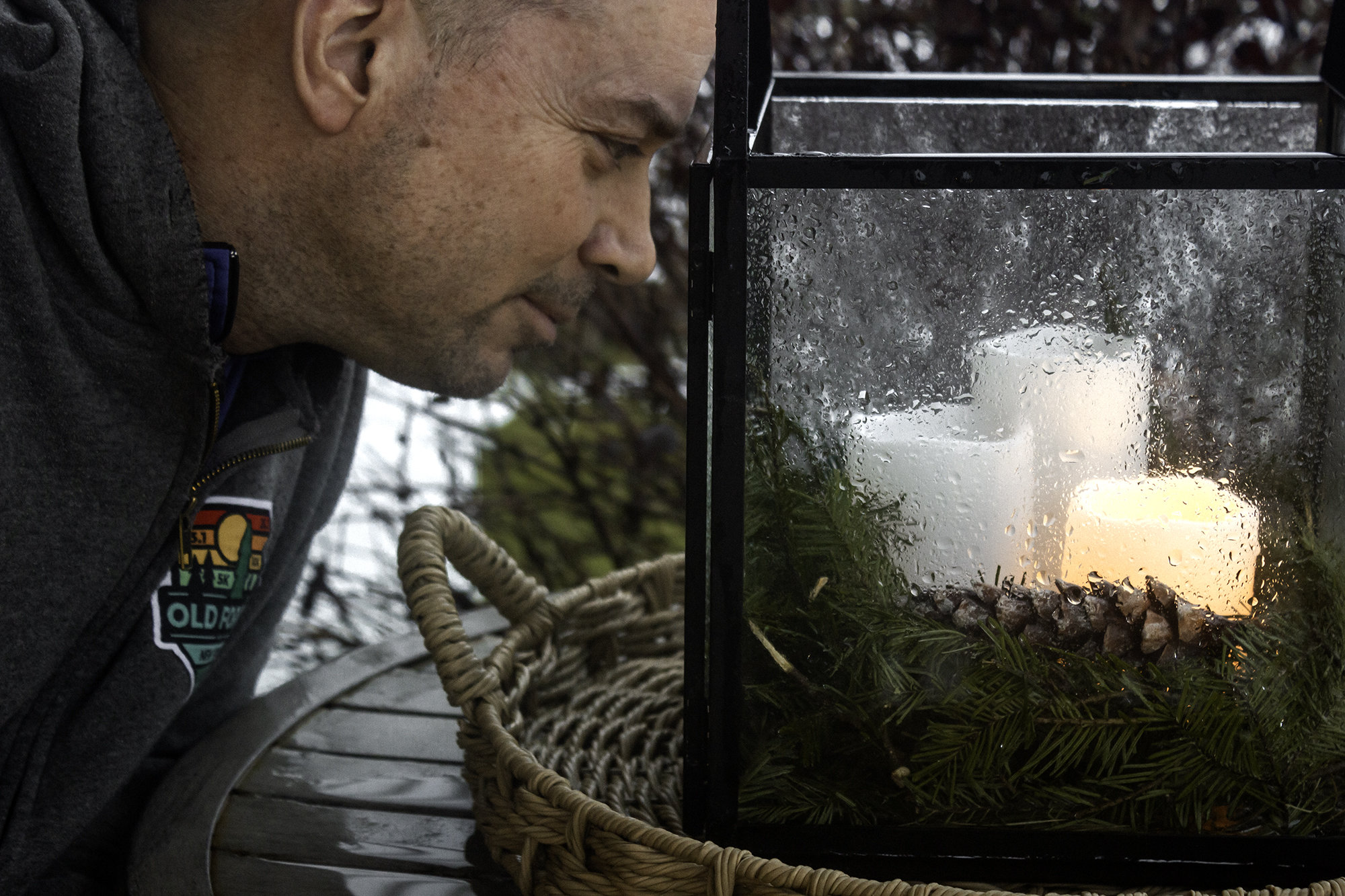 Picture of a man looking into a rainy glass candle container.