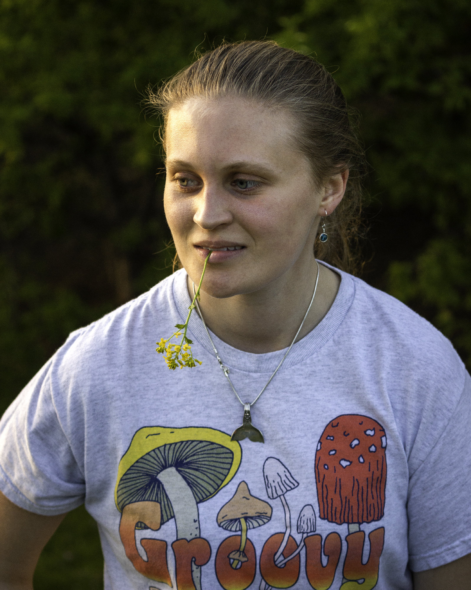 Portrait of a young woman with a flower in her mouth.