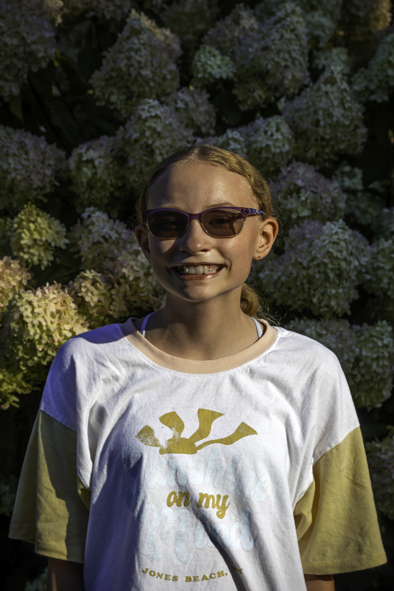 Portrait of a young lady at golden hour in front of a hydrangea plant.