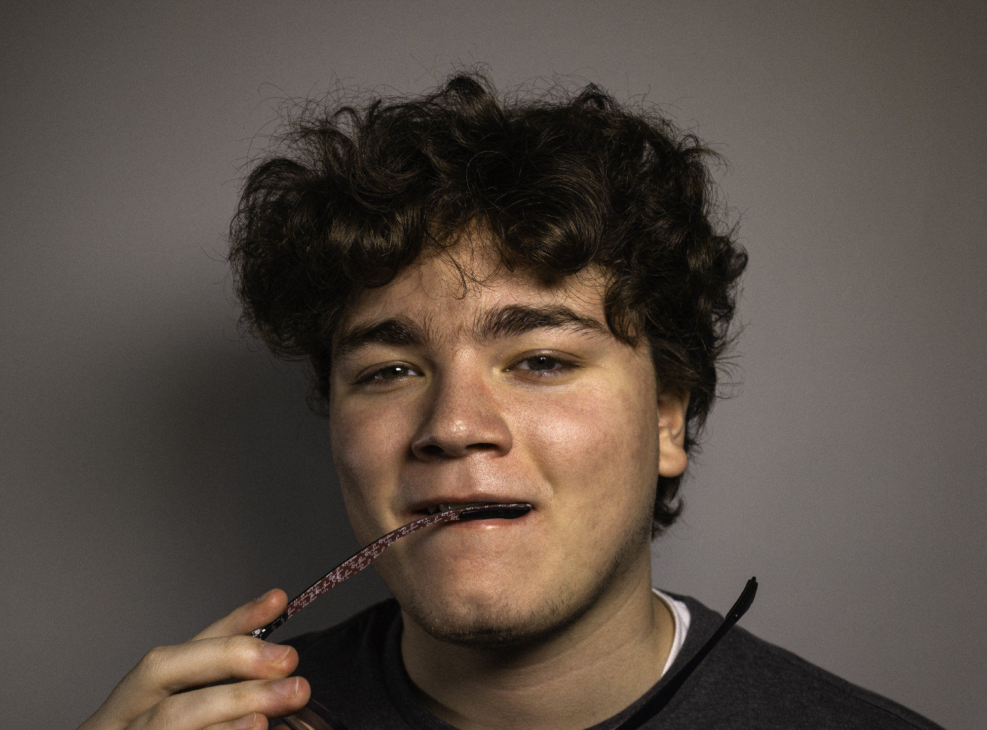 Portrait of Jacob biting one end of his glasses.