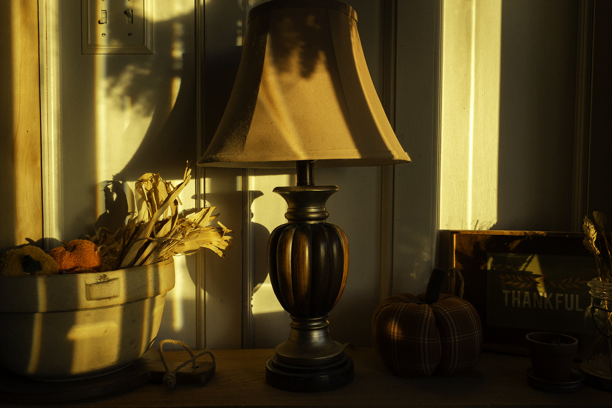 Picture of a bowl, a lamp, and some fall-themed decorations during golden hour.